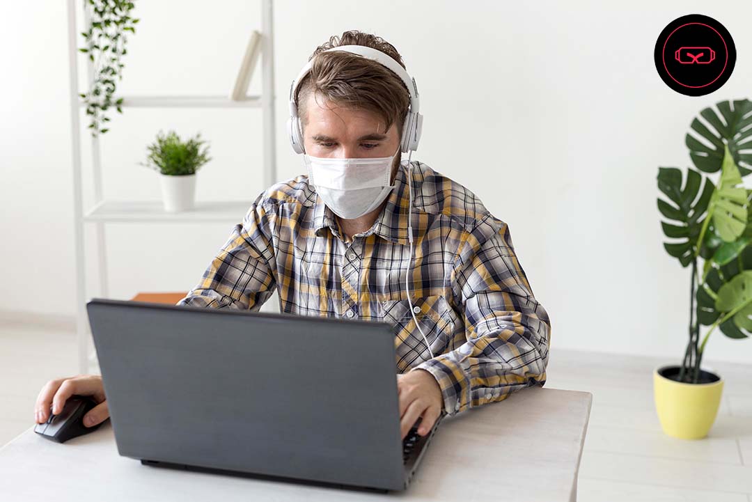 Image of a man wearing a mask and working with his laptop